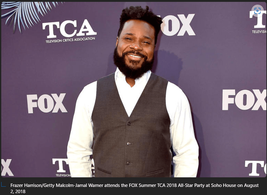 Image of Malcom-Jamal Warner standing in front of a backdrop with the word "Fox" on it along with "TCA". Credit for the image reads, Frazer Harrison/Getty Malcolm-Jamal Warner attends the FOX Summer TCA 2018 All-Star Party at Soho House on August 2, 2018